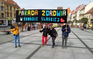 4 osoby trzymające transparent "Parada Zdrowia w Środzie Śląskiej na średzkim rynku