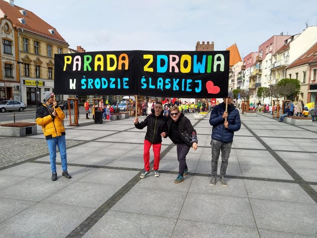 4 osoby trzymające transparent "Parada Zdrowia w Środzie Śląskiej na średzkim rynku